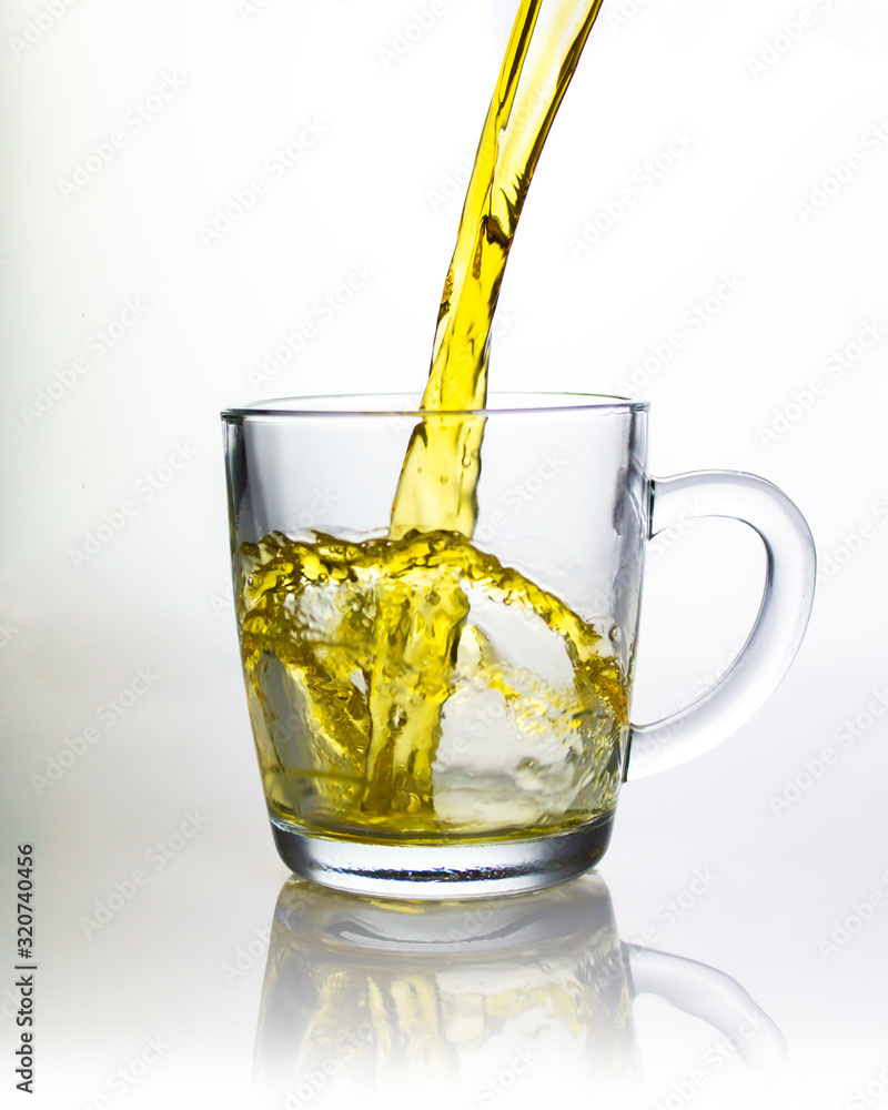 A splash of green tea in a transparent glass, beautiful splashes flying in an arc, pouring tea liquid drink. A splash of green tea in a transparent glass, beautiful splashes flying in an arc, pouring tea liquid drink.