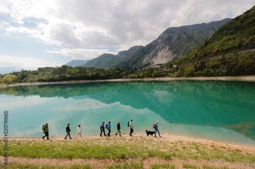 Gruppo di persone camminano sulla costa di un lago