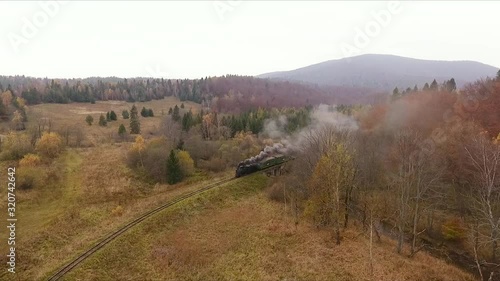 Old vintage train(locomative) moving through the breathtaking forest railway, mountains landscape, autumn colors, drone shot  photo