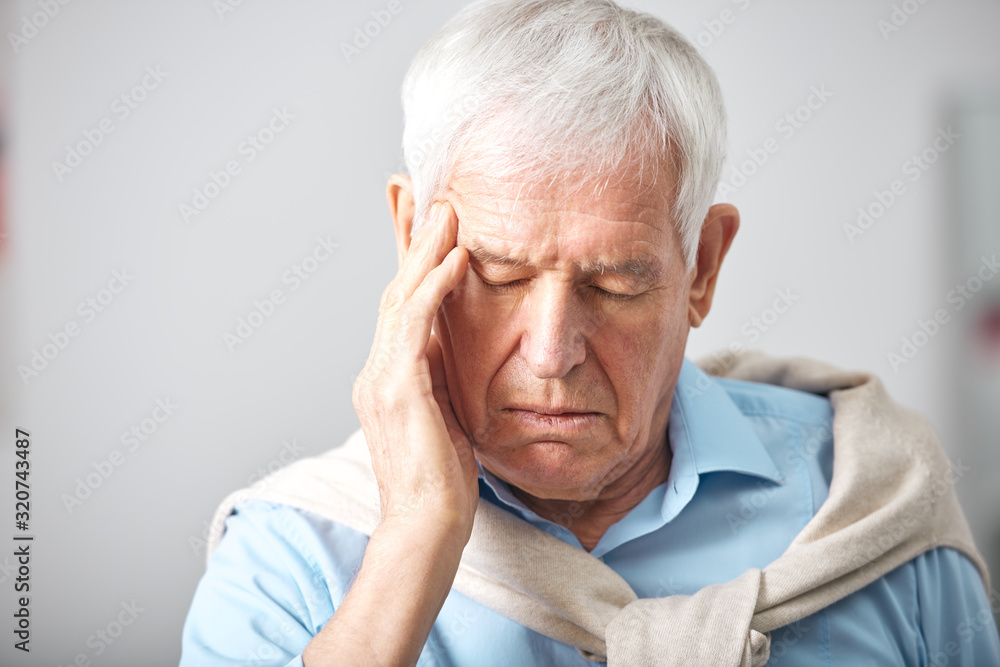 Sick senior man with whte hair and closed eyes touching head while having headache or expressing tiredness Sick senior man with whte hair and closed eyes touching head while having headache or expressing tiredness