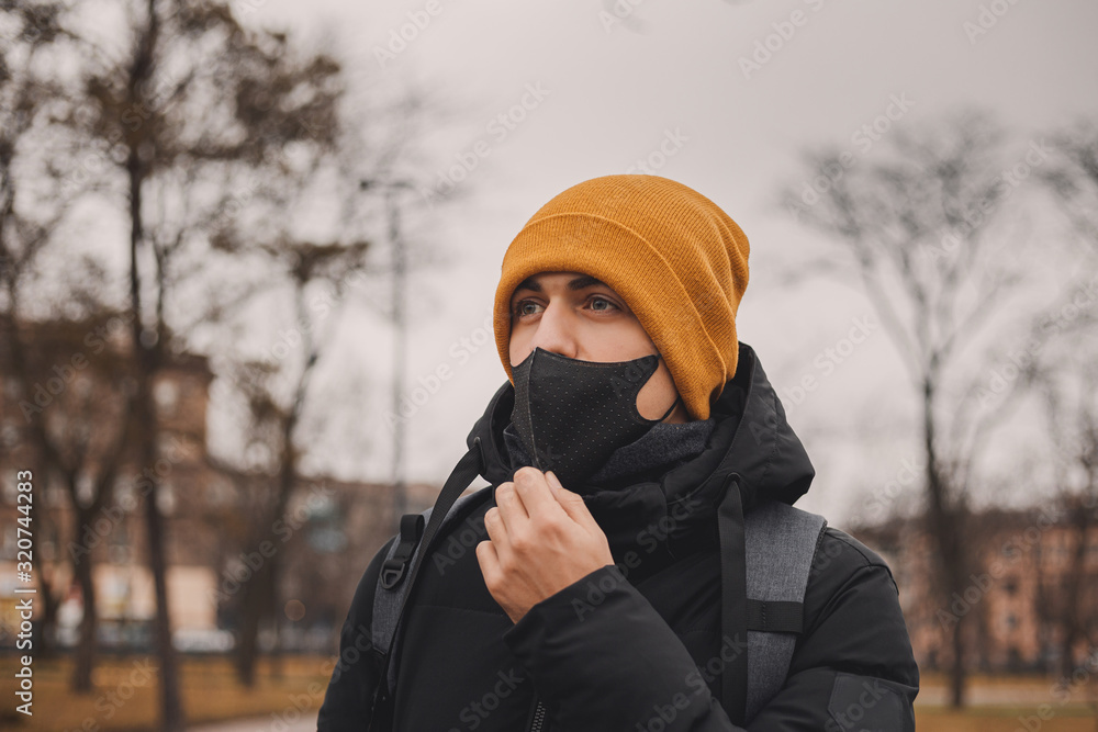 Man in orange hat takes off black medical mask on the street. Coronavirus is a virus that is endemic in China. Protection from the illness for children. Health safety concept. Man in orange hat takes off black medical mask on the street. Coronavirus is a virus that is endemic in China. Protection from the illness for children. Health safety concept.