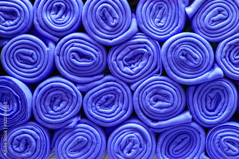 Pile of folded blue blankets. Rolls of blue plaids lie on a shelf, texture effect. Pile of folded blue blankets. Rolls of blue plaids lie on a shelf, texture effect.