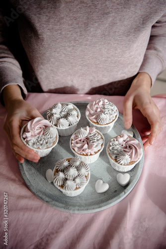 Woman holding tasty homemade cupcakes. Vanilla muffin cupcake with cream buttercream icing. Birthday cupcake. Valentine sweets.  Close up view delicious sweet dessert