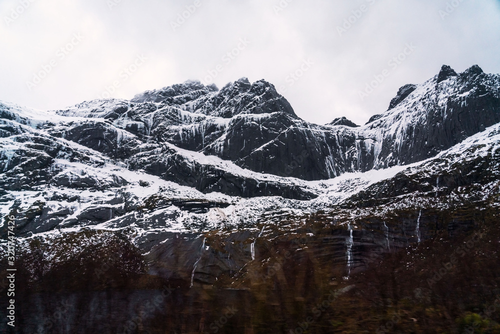 Obraz premium Numerous waterfalls flows downside mountains. Winter landscape photography of Lofoten islands nature, Norway.