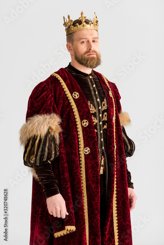 handsome king with crown looking at camera isolated on grey photo