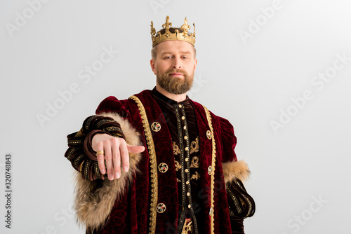 handsome king with crown showing hand isolated on grey photo