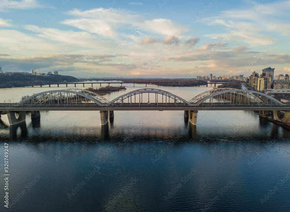 Naklejka premium Aerial drone view. Darnitsky railway-automobile bridge in Kiev in the sunset light.