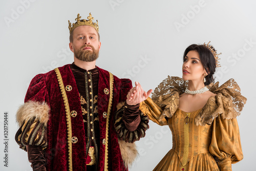 queen and king with crowns holding hands isolated on grey