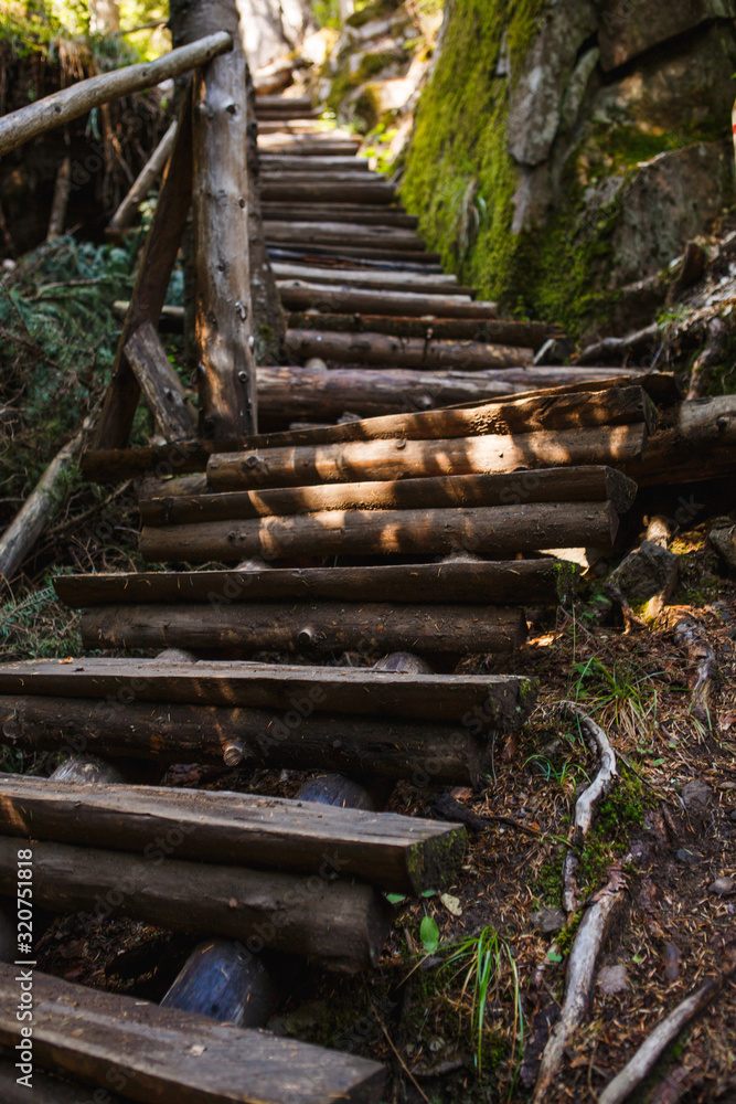 Wooden bridge with steps on the eco-trail along the rocks and mountain river in Bulgaria, Smolyan city. Equipped tourist road through the forest for sightseeing tours and walks Wooden bridge with steps on the eco-trail along the rocks and mountain river in Bulgaria, Smolyan city. Equipped tourist road through the forest for sightseeing tours and walks