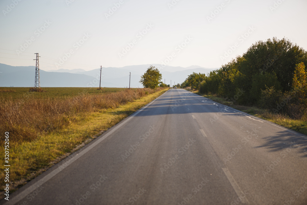 Asphalt road in the mountainous region of Bulgaria. Asphalt with cracks - mountain serpentine with sharp turns through the forest and field Asphalt road in the mountainous region of Bulgaria. Asphalt with cracks - mountain serpentine with sharp turns through the forest and field