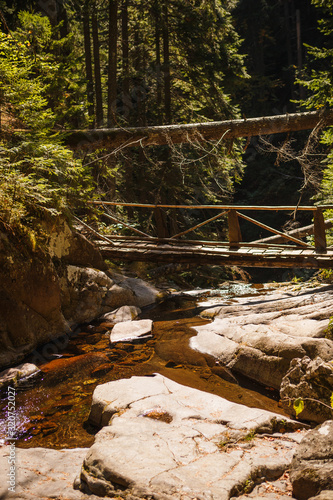 Wooden bridge with steps on the eco-trail along the rocks and mountain river in Bulgaria, Smolyan city. Equipped tourist road through the forest for sightseeing tours and walks
