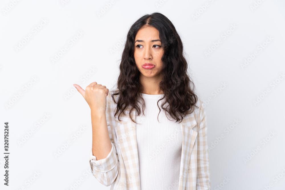 Mixed race woman over isolated white background unhappy and pointing to the side Mixed race woman over isolated white background unhappy and pointing to the side