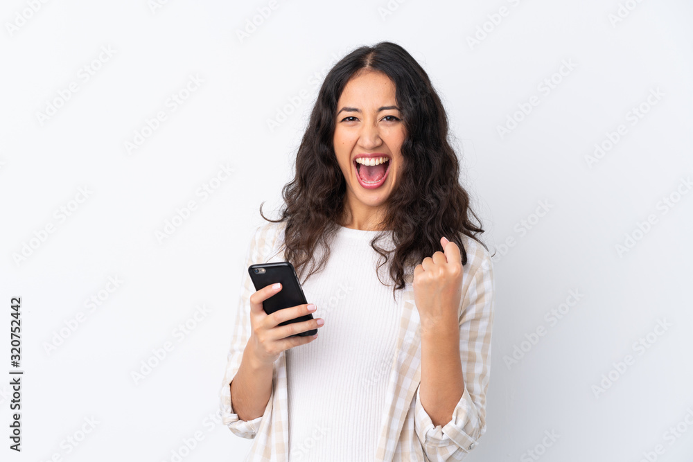 Mixed race woman over isolated white background with phone in victory position Mixed race woman over isolated white background with phone in victory position