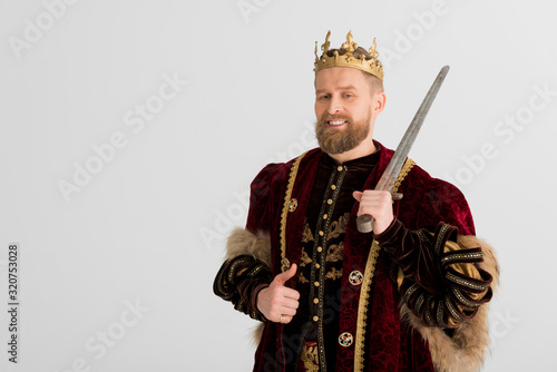smiling king with crown holding sword and showing like isolated on grey