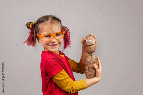 Freakish kid holds misshapen wrong color fruits and vegetables, waste food concept photo