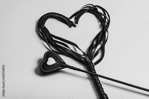 Card for Valentine's Day. BDSM riding crop and leather whip in the form of a heart. Sex toys for love games. photo