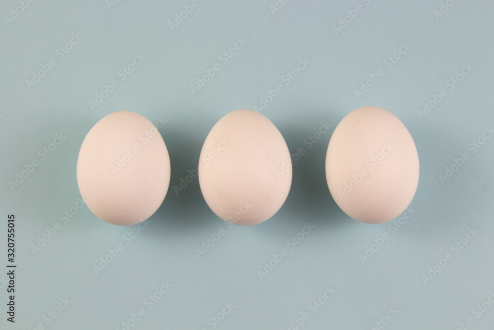 Three white chicken eggs on a blue background. place for text, easter holiday concept Three white chicken eggs on a blue background. place for text, easter holiday concept