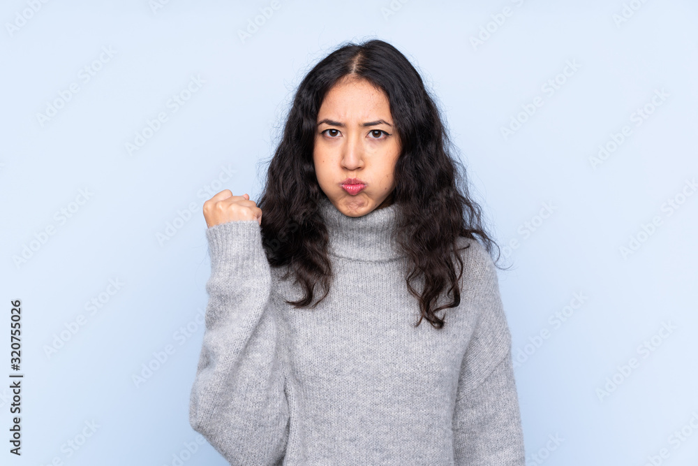 Spanish Chinese woman over isolated blue background with angry gesture Spanish Chinese woman over isolated blue background with angry gesture