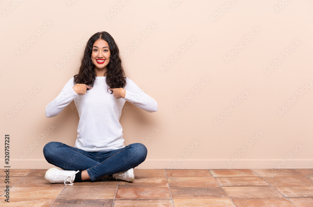 Young woman sitting on the floor with surprise facial expression Young woman sitting on the floor with surprise facial expression