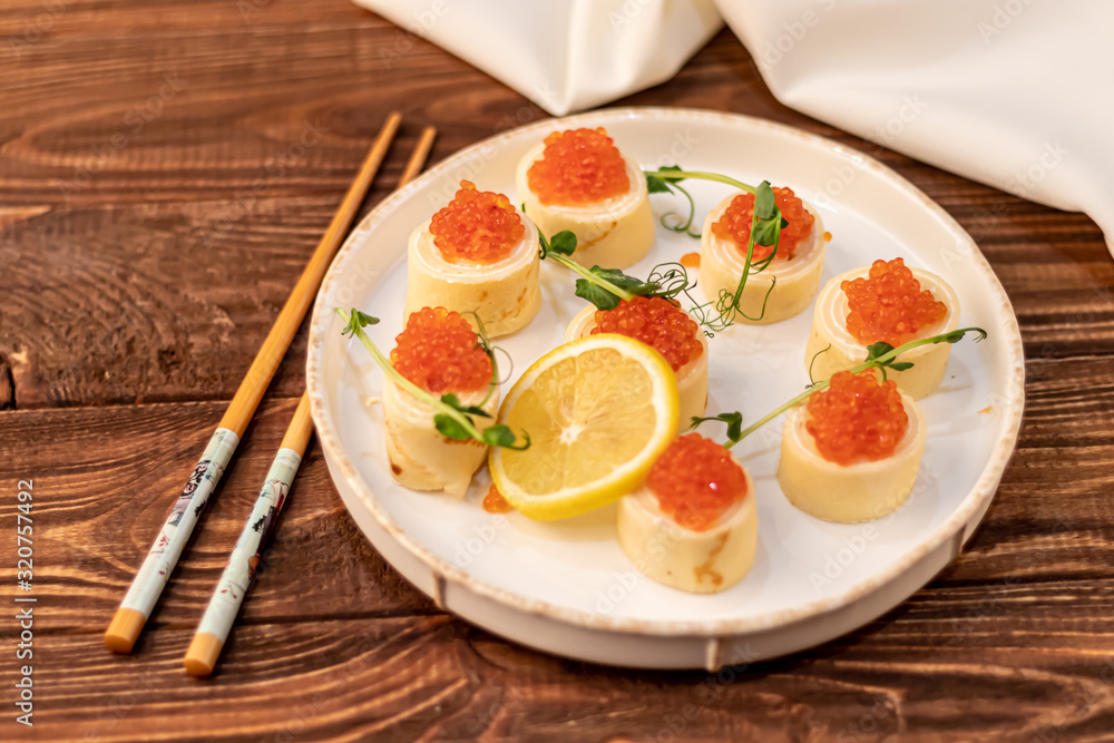Dough rolls with cheese, red caviar. Garnished with sprigs of microgreen, a slice of lemon. On a wooden natural background. Dough rolls with cheese, red caviar. Garnished with sprigs of microgreen, a slice of lemon. On a wooden natural background.