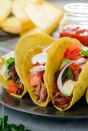 Closeup on hard-shell tacos garnished with sour cream