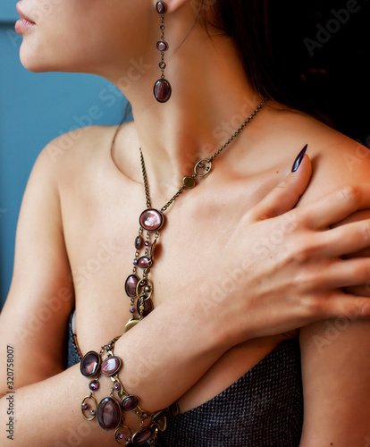Hands and body of a girl decorated with different decorative jewelry. Bracelet on a hand close-up. Necklace with stones on the neck. Stylish accessories.