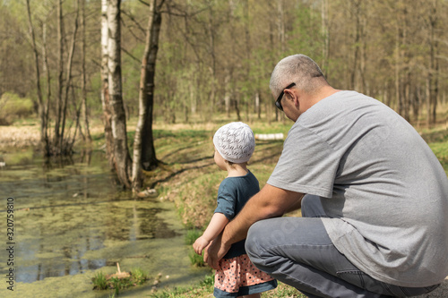 dad and daughter admire the spring forest lake covered with green duckweed © Елена Гурова