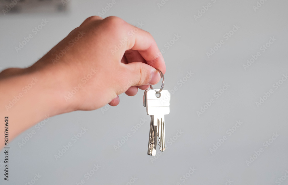closeup and portrait of hand and arm of man or woman holding two keys - living alone and independent lifestyle and concept closeup and portrait of hand and arm of man or woman holding two keys - living alone and independent lifestyle and concept