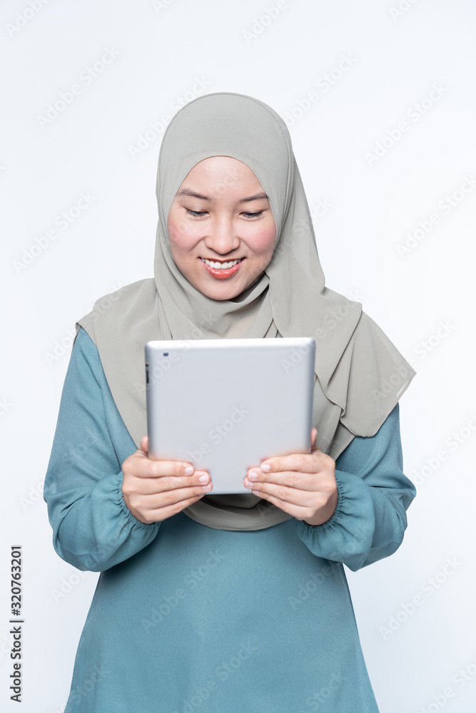 Female muslim woman using a tablet device. Female muslim woman using a tablet device.