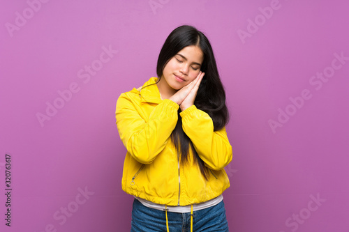 Young teenager Asian girl over isolated purple background making sleep gesture in dorable expression © luismolinero