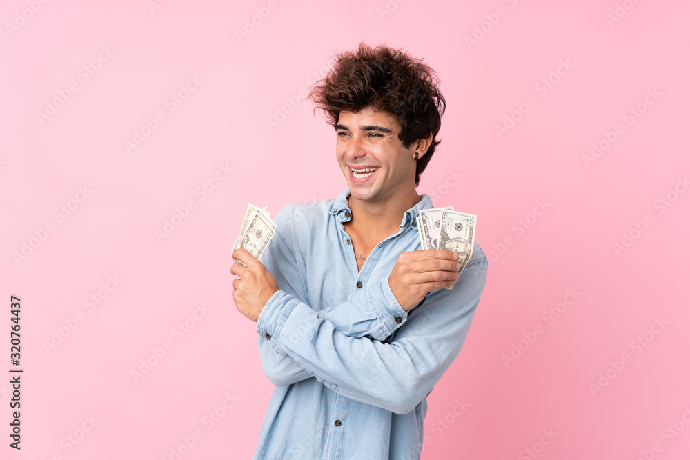 Young caucasian man over isolated pink background taking a lot of money Young caucasian man over isolated pink background taking a lot of money