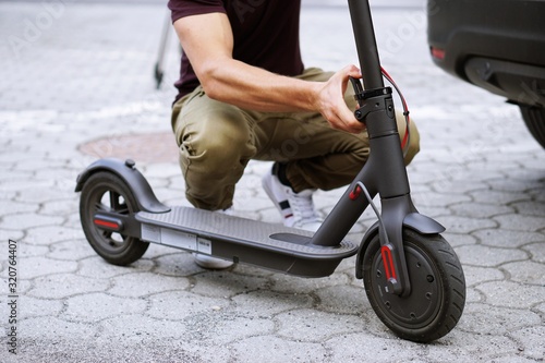 Man pulls electric scooter out of car.