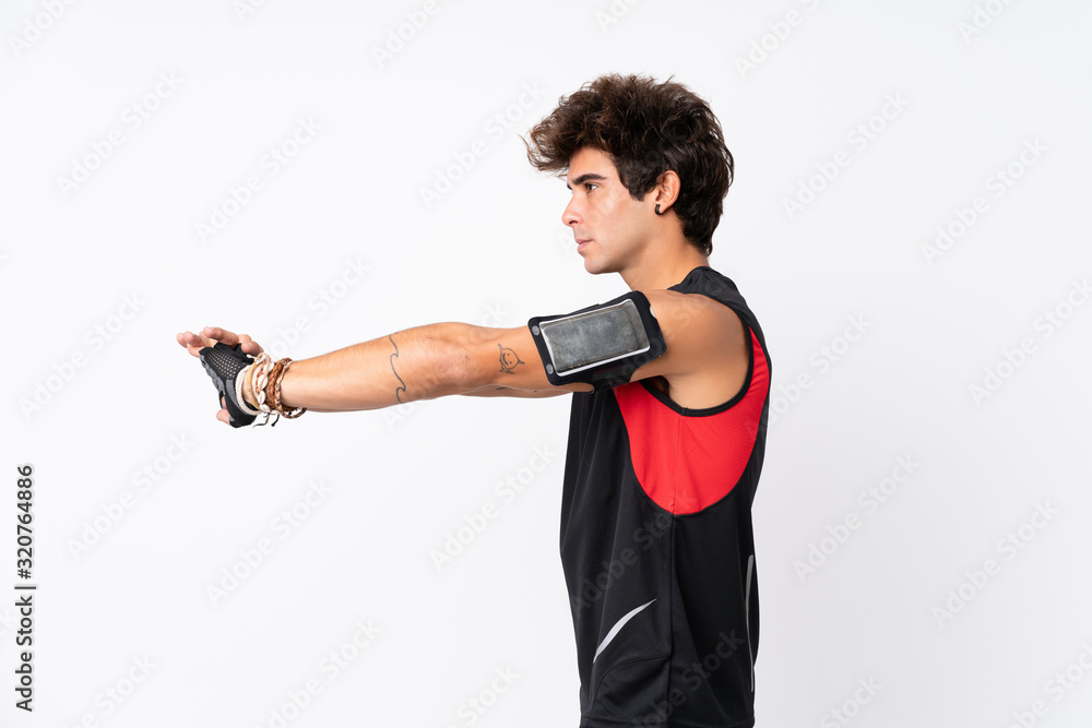 Young sport man with tattoos over isolated white background stretching arm