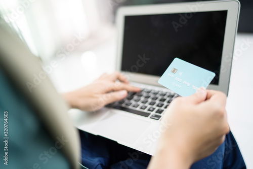 Female muslim woman using laptop while holding credit card.