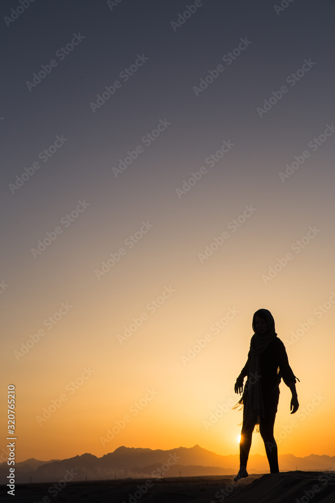women sihouette with long scarf during sunset in desert in Yazd, Iran