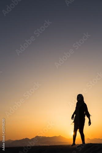 women sihouette with long scarf during sunset in desert in Yazd, Iran