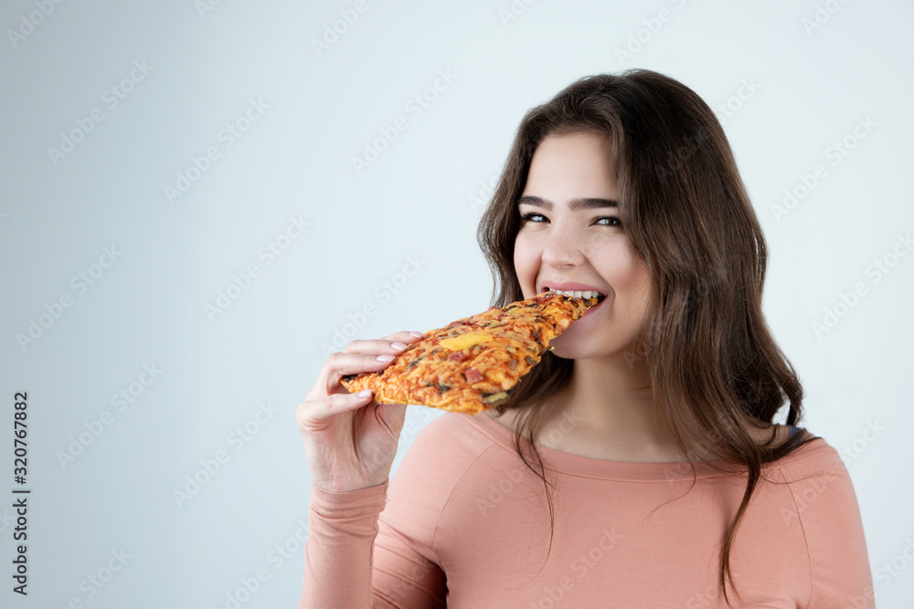 young beautiful woman biting slice of pizza in one hand looking happy being on diet isolated white background young beautiful woman biting slice of pizza in one hand looking happy being on diet isolated white background