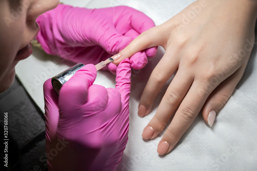 Nail artist applying gel on the nails. photo