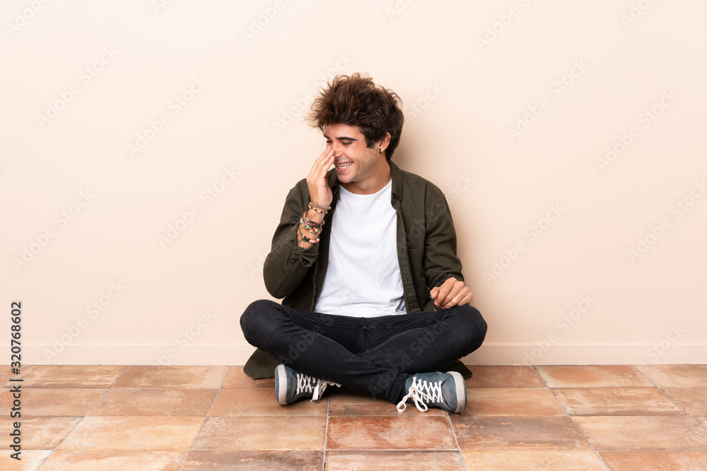Young caucasian man sitting on the floor smiling a lot Young caucasian man sitting on the floor smiling a lot