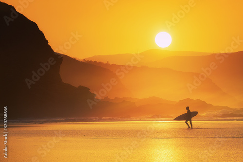 surfer exiting water at misty sunset © mimadeo