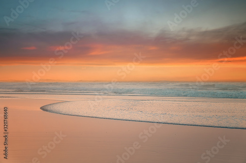 beautiful sunset on beach with a wave on the shore