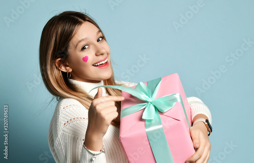 Foto Smiling teen kid girl celebrate valentines day holding a big pink present gifts
