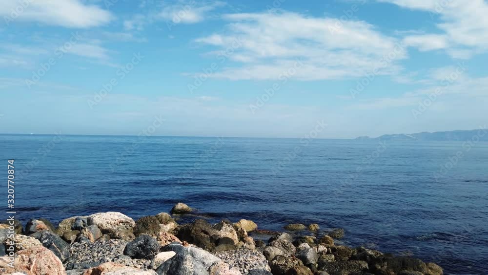 Picturesque landscape on the volcanic island of Crete. Parallax effect. Huge stones move against the background of the sea and blue sky. Dolly shot. Picturesque landscape on the volcanic island of Crete. Parallax effect. Huge stones move against the background of the sea and blue sky. Dolly shot.