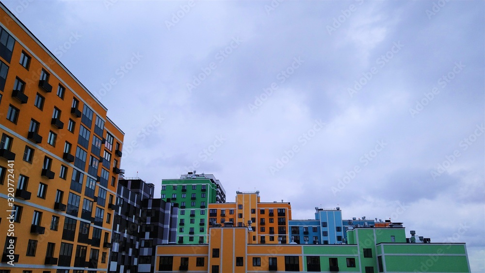Bright multi-colored multi-storey residential building against a cloudy white sky