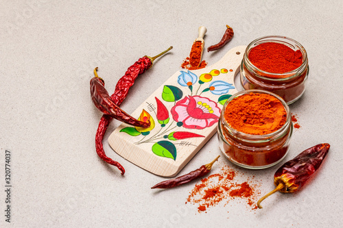 Magyar (Hungarian) red sweet and hot paprika powder. Traditional pattern on a cutting board, different varieties of dry pepper. Stone concrete background photo