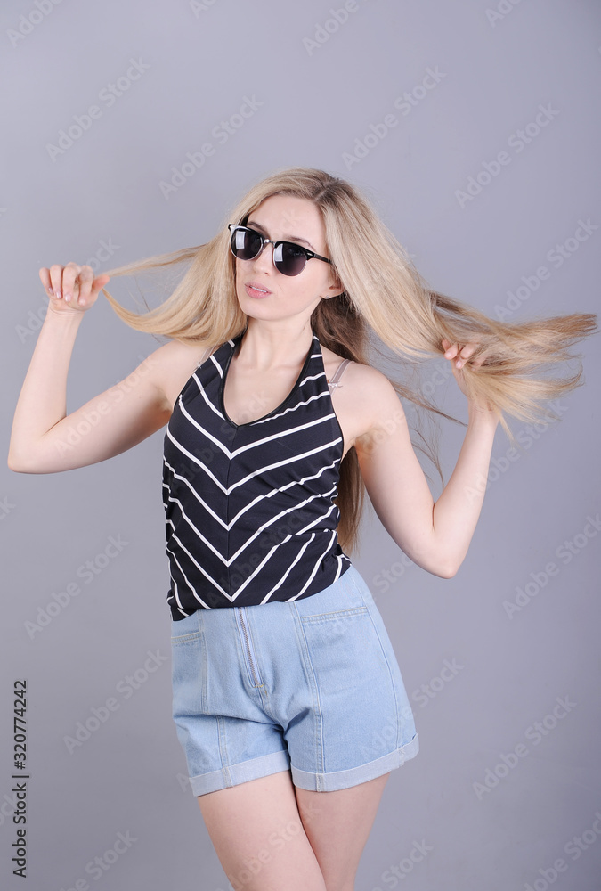 Stylish smiling woman posing on grey background. Stylish smiling woman posing on grey background.