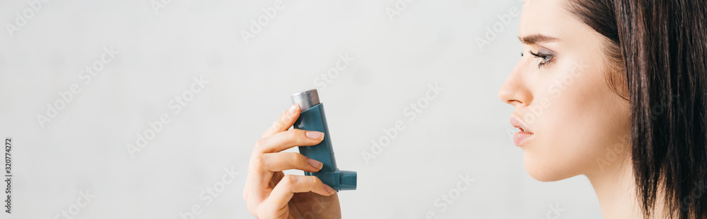 Side view of young woman holding inhaler on white background, panoramic shot Side view of young woman holding inhaler on white background, panoramic shot