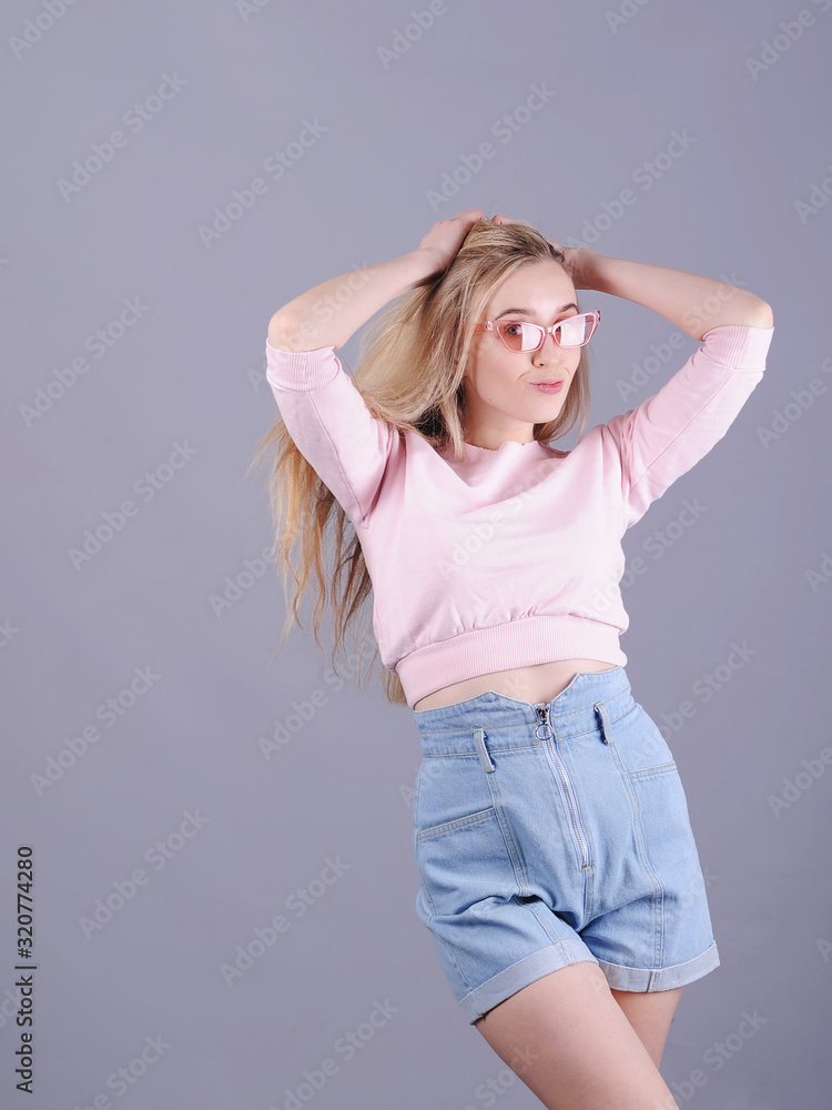 Stylish smiling woman posing on grey background. Stylish smiling woman posing on grey background.