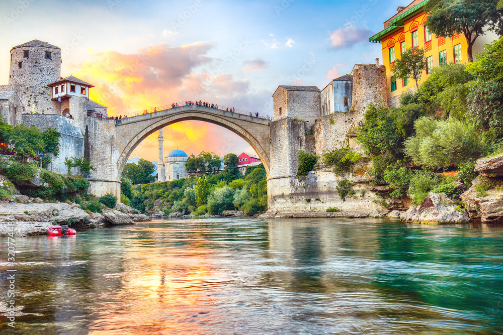 Fantastic Skyline of Mostar with the Mostar Bridge, houses and minarets, at sunset
