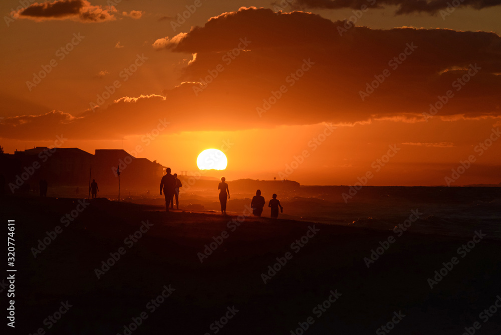 Silhouettes of people at sunset on the Atlantic ocean